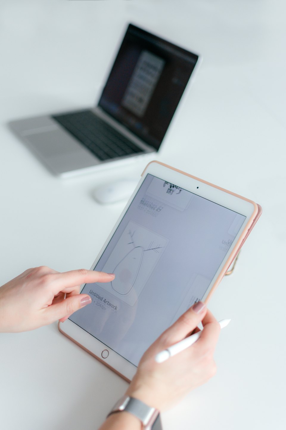 Mani che usano un tablet e uno stilo su una scrivania bianca.